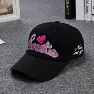 Close-up detail of the black baseball cap featuring pink glitter embroidered Sweetie text and heart.