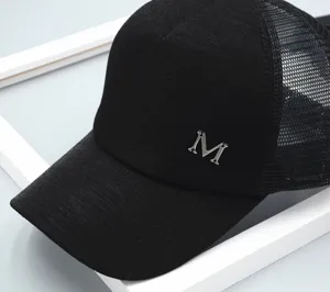 Detailed view of black mesh baseball cap featuring a stylish metallic M letter decoration.