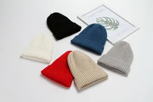 Detailed view of multiple colored knitted beanies in black, white, blue, red, khaki, gray.