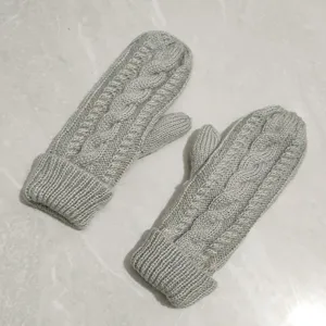 Close-up of cozy grey knitted mittens featuring a classic cable pattern and warm cuff detail.
