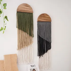 Close-up detail of bohemian handmade macrame wall hanging with wooden semi-circle top and tassels.