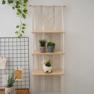 Close-up details of the boho macrame wall hanging shelf with three wooden boards and plants.