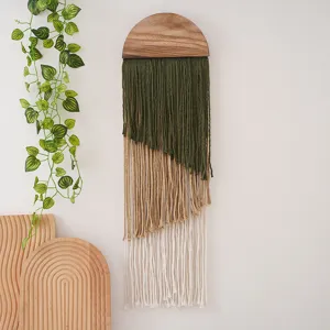 Boho wall hanging detail, semicircle wood top with multi-layer green, khaki, and white tassels.