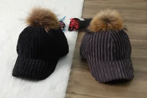 Winter corduroy baseball cap with large faux fur pom pom, warm thick plush hat detail view.