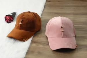 Velvet baseball cap detail showing brown and pink styles with stylish metal chain and ring decor.