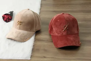 Velvet baseball cap detail showing corduroy texture, metallic ring bar accent, and warm winter style.