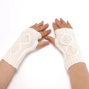 Close-up detail of white cable knit fingerless gloves showing soft texture and diamond pattern.