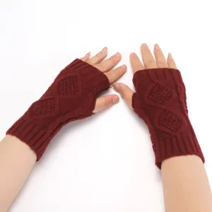 Close-up detail of winter knitted fingerless gloves in burgundy with classic diamond pattern.