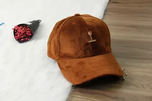 Close-up detail of the brown velvet baseball cap showcasing metal chain and ring decorations.