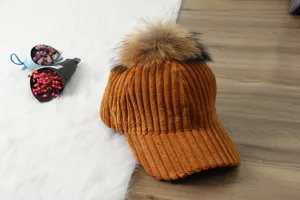 Corduroy baseball cap for women with large fur pom-pom, thick warm winter hat detail.