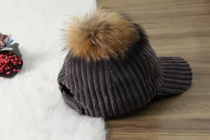 Detailed view of the winter warm dark grey corduroy baseball cap with fluffy faux fur pom pom.