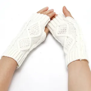 Detailed view of white winter knitted fingerless gloves with a classic diamond pattern design.