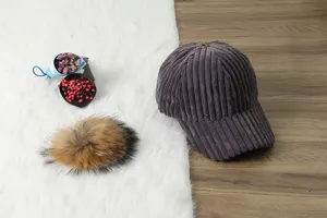 Detailed shot of a women's corduroy baseball cap with a fluffy pompom and floral props.