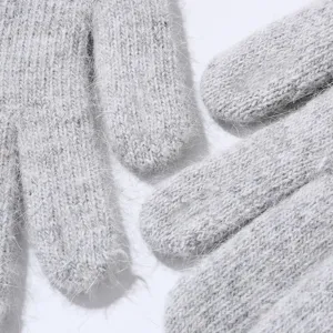 Close-up of grey fuzzy knit winter gloves, soft plush texture, warm five-finger design.