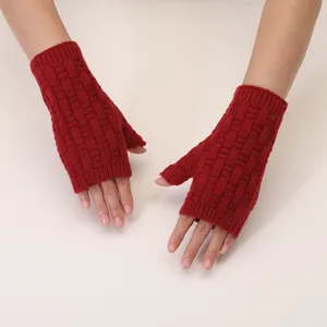Close-up view of red knitted fingerless gloves showing the textured jacquard pattern.