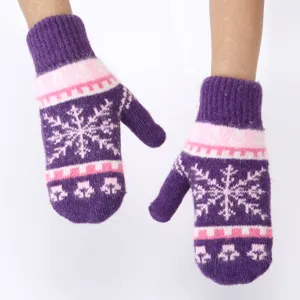 Close-up detail of winter warm knitted mittens with purple and pink snowflake pattern.