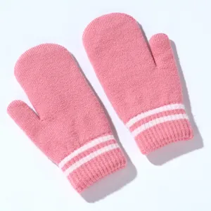 Close-up detail of pink winter knitted mittens with white stripes, cozy warm gloves.
