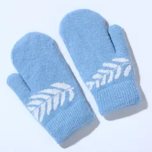 Close-up detail of soft winter fluffy mittens in light blue with cute white leaf pattern.