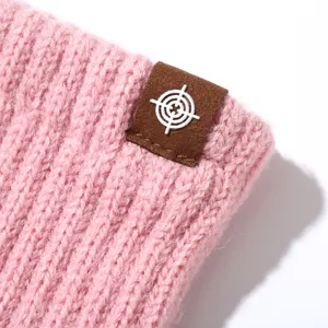 Close-up of pink knit winter glove detail, featuring soft wool texture and a stylish leather patch.