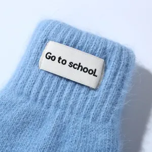 Close-up detail of soft fuzzy winter knit gloves in light blue with a stylish sewn label.