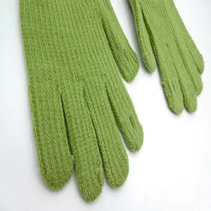 Close-up detail of green knitted gloves showcasing fine wool texture and warm fabric.