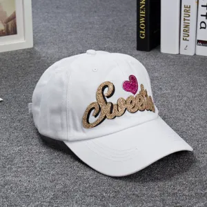 Women white baseball cap with gold glitter Sweetie embroidery and pink heart patch.