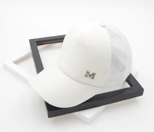 White mesh baseball cap detail view, breathable summer trucker hat with metallic M letter.