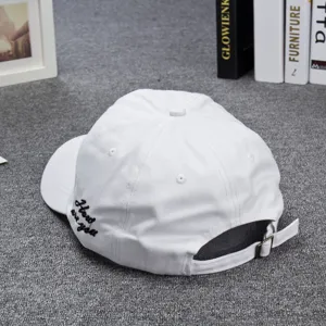 Close-up detail of white baseball cap showcasing side embroidery lettering and metal buckle.
