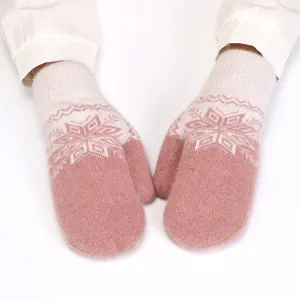 Close-up detail of cozy pink and white knit winter mittens with snowflake pattern for warmth.