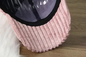 Close-up view of pink corduroy baseball cap detail, featuring textured fabric and visor.