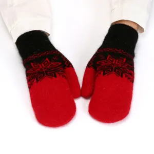 Close-up detail of winter warm red and black knitted fluffy mittens with Nordic snowflake pattern.