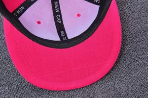 Nahaufnahme der Innenseite einer pinken Cap mit schwarzem Band und sauberen Nähten.
