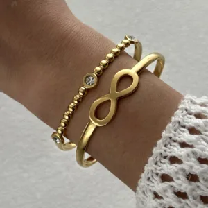 Vue détaillée de bracelet jonc infini et perlé en acier inoxydable doré, accessoire élégant.