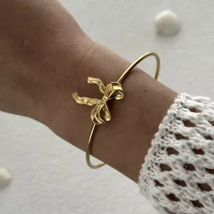 Détail de bracelet nœud doré, design de manchette ouvert élégant, accessoire de poignet chic.