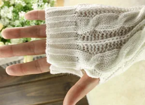 Close-up detail of cream white knitted arm warmer showing soft cable knit texture and fit.