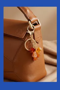 Detailopname van natuurlijke edelsteen kristal sleutelhanger bungerend aan stijlvolle leren tas.