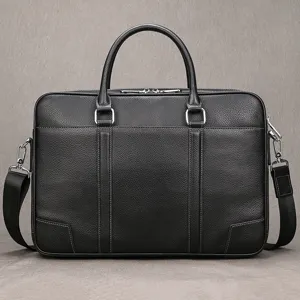 Black cowhide leather business briefcase detail showing fine texture, metal hardware and handles.