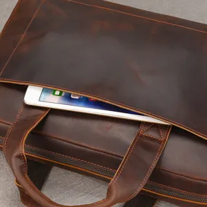Primo piano dei dettagli di una ventiquattrore da uomo in pelle marrone con tasca frontale.
