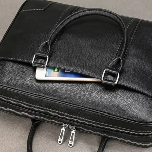 Detailed view of black leather business briefcase, showing fine texture and double zippers.