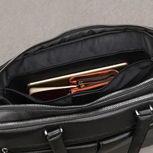 Detalle interior del maletín de negocios de cuero negro para hombre con gran capacidad y bolsillos.