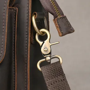 Detailaufnahme einer Vintage Herren Ledertasche mit Messing Karabinerhaken und Gurt.
