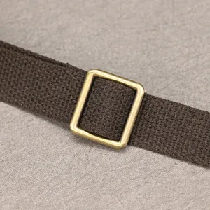 Detailaufnahme des braunen Taschenriemens aus robustem Stoff mit vintage Messing Schnalle.