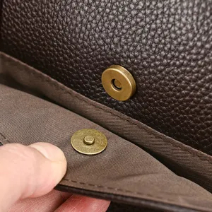 Vista dettagliata dell'interno della borsa in pelle marrone, con bottone magnetico e trama.