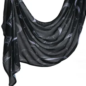 Detailed close-up of black rayon scarf with celestial moon and star print draping fabric.