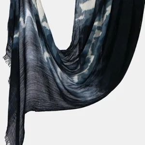 Detail view of lightweight tie-dye wrinkled scarf with gradient blue pattern and fringe.
