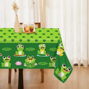 Detailed view of green cartoon frog party tablecloth in home dining scene, vibrant print.