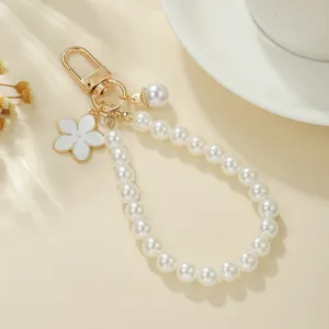 Detaillierte Nahaufnahme von Perlen-Schlüsselanhänger mit weißem Blumen-Anhänger und goldenem Haken.