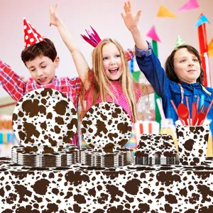 Cow print party tableware set detail view featuring disposable plates, cups, and tablecloth.