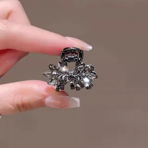 Gros plan détaillé d'une mini pince à cheveux en cristal étincelant avec une finition métal sombre.