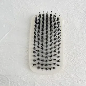 Detail view of oval beard brush with soft black bristles and rounded tips for men's styling.